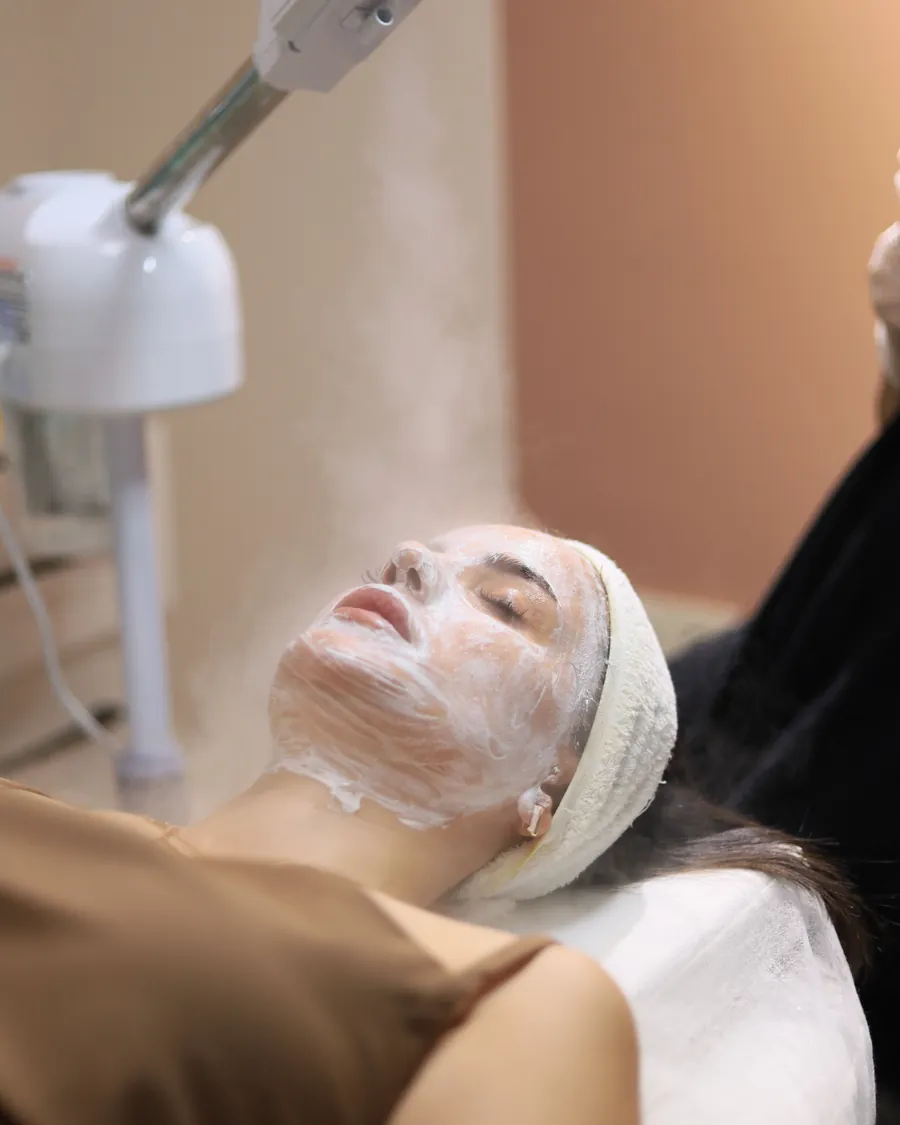 Cliente com máscara facial sob o vapor de ozônio, na sala de atendimento